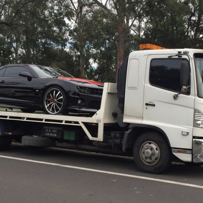 A towing truck with a black sedan car.